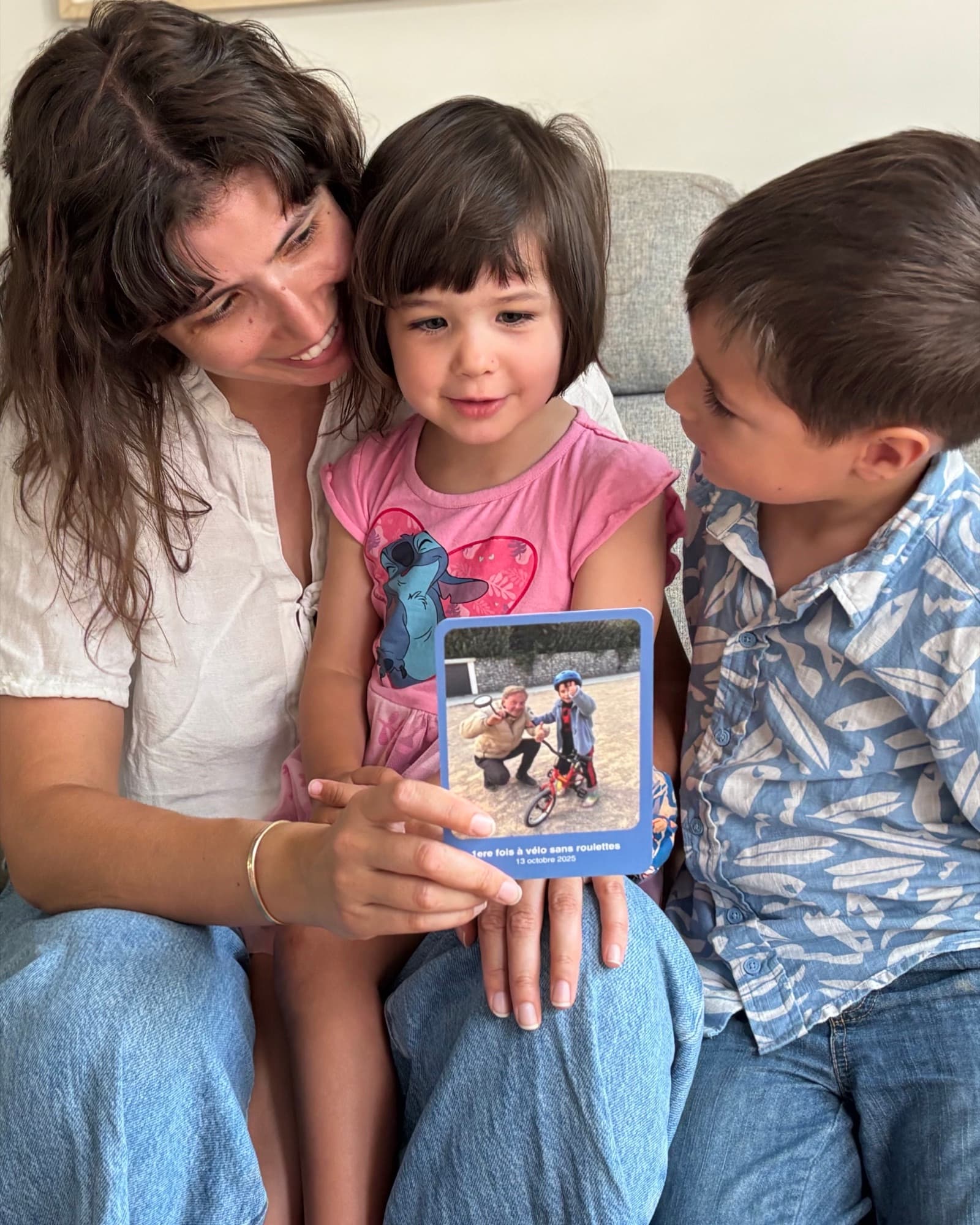 Une maman et ses deux enfants regardent ensemble une carte souvenir Zaza.
